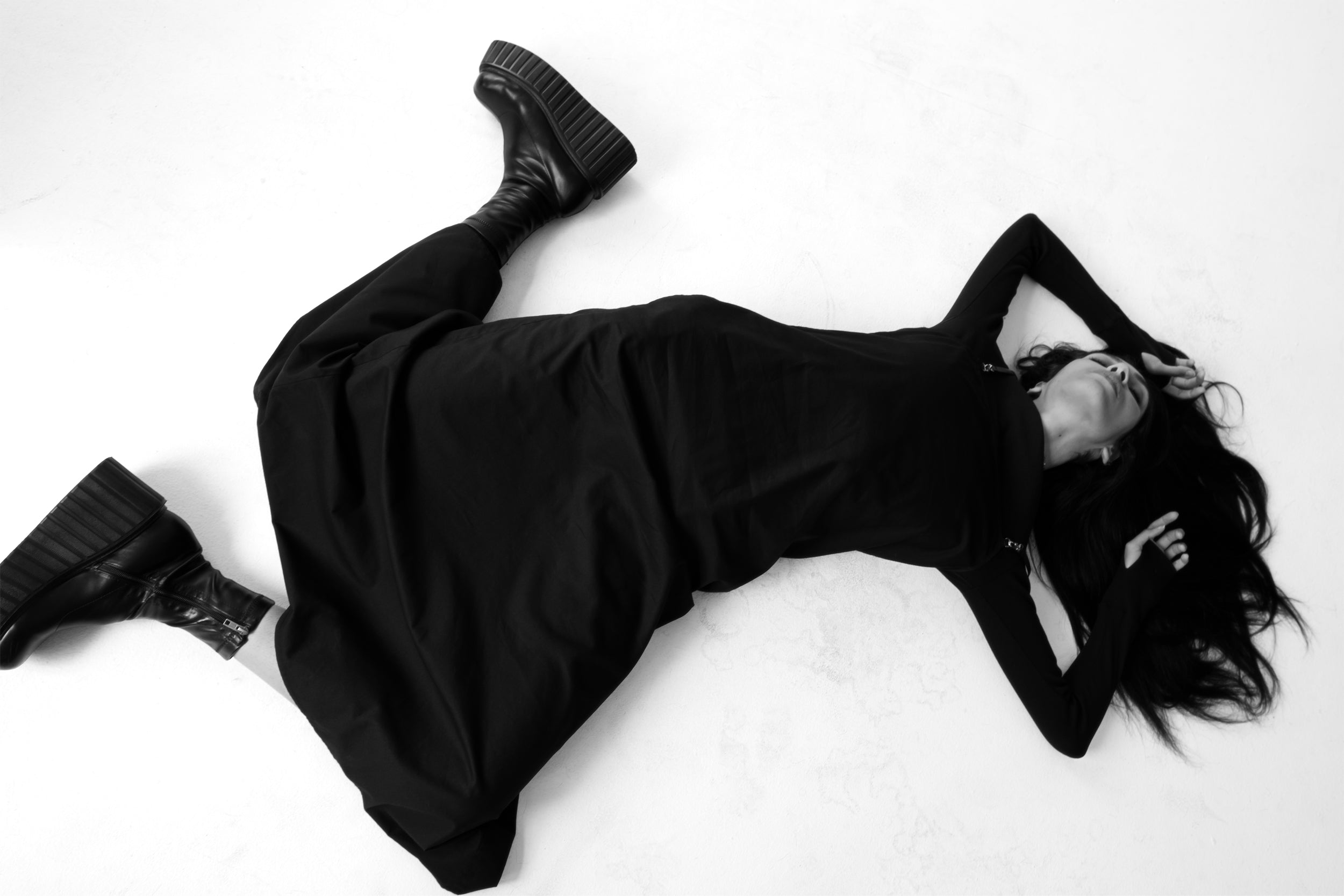 Woman laying down wearing the Polokwane black maxi dress over the Sapporo black long sleeve dress